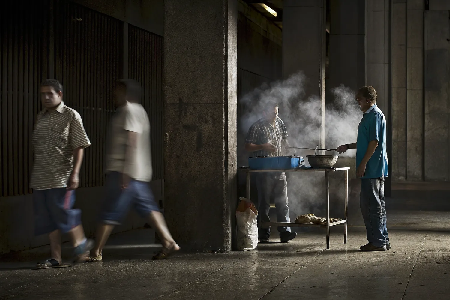 A covered street food stall wreathed in steam at night as the journey begins